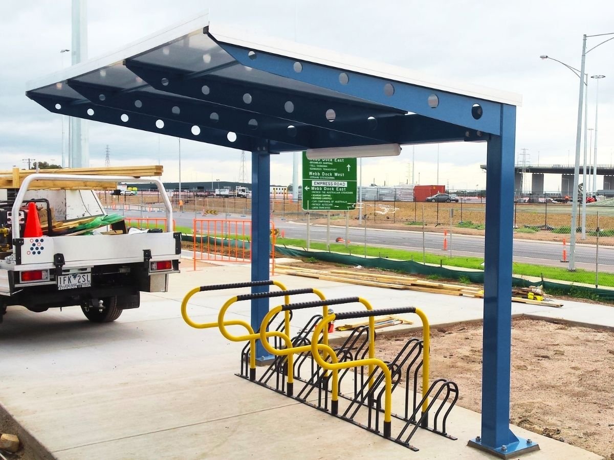 Parqueadero para bicicletas en exteriores con techo azul y racks alineados, pensado para orden y seguridad.